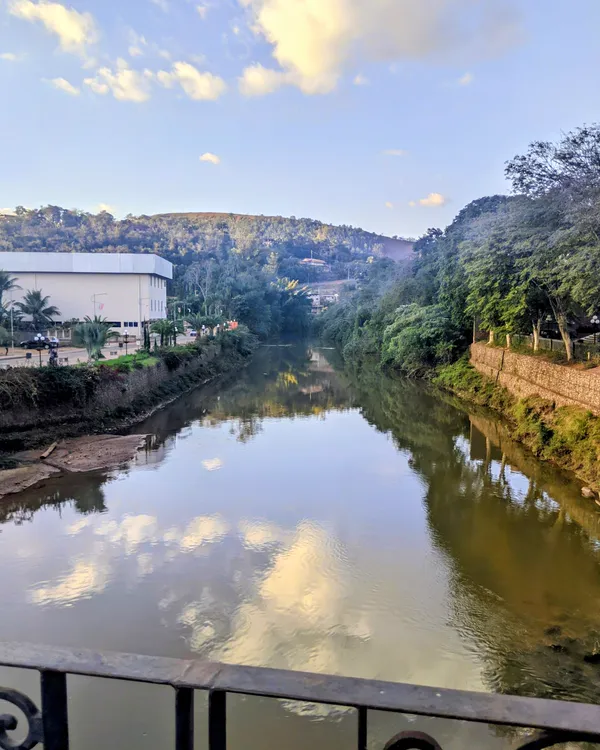 O Rio Piracicaba refletindo o céu, entre morros e árvores