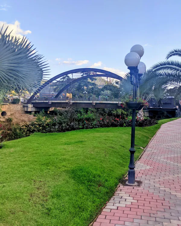 Ponte azul em arco e jardim com postes de luz