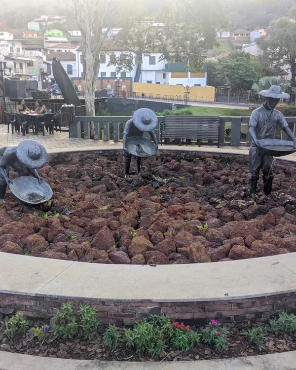 Estátuas de garimpeiros com bateia em canteiro de praça