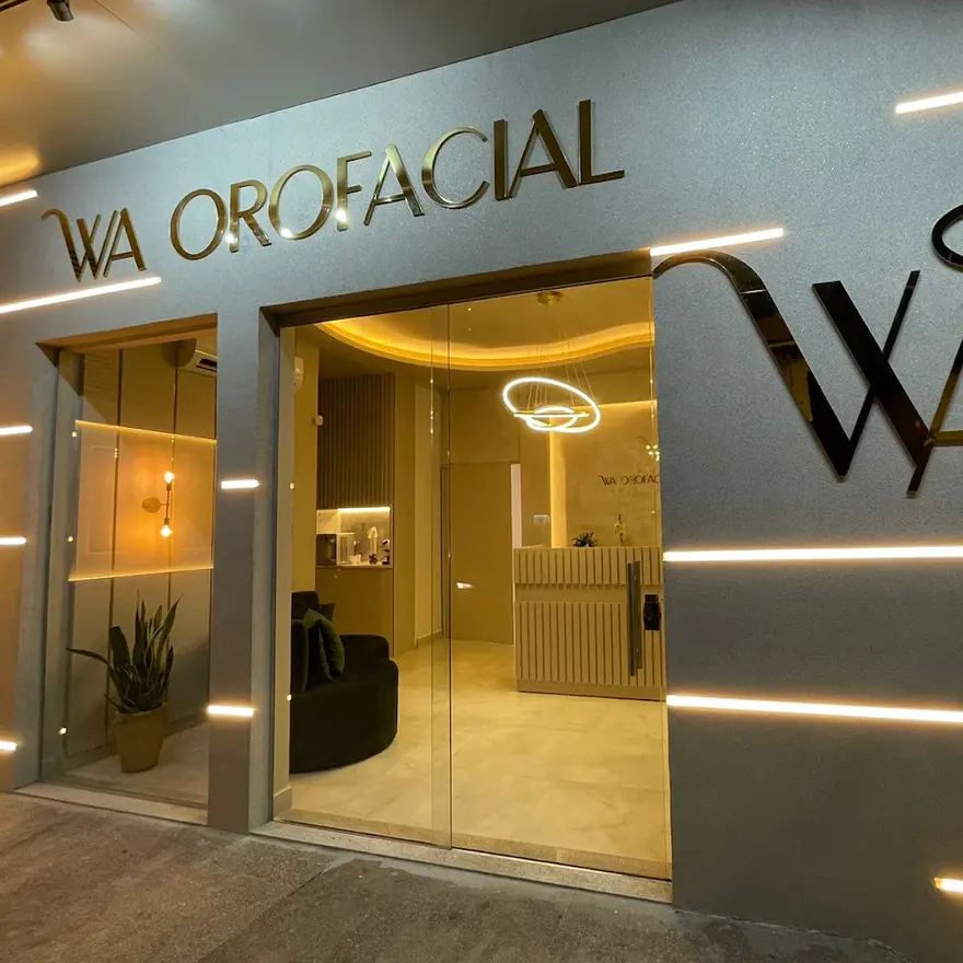 Fachada da WA Orofacial à noite, com o letreiro dourado e o WA gigante na parede