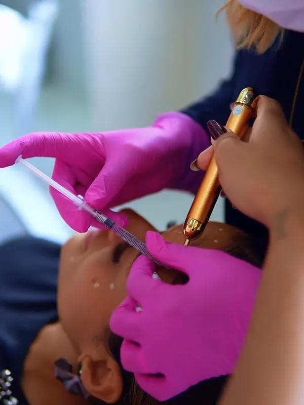 Aplicação de toxina botulínica na testa de uma paciente, com luvas rosa